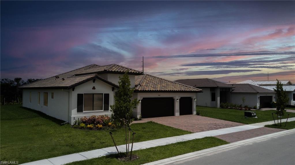 Mediterranean / spanish-style house featuring decorative driveway, a garage, a front lawn, stucco siding, and a tile roof