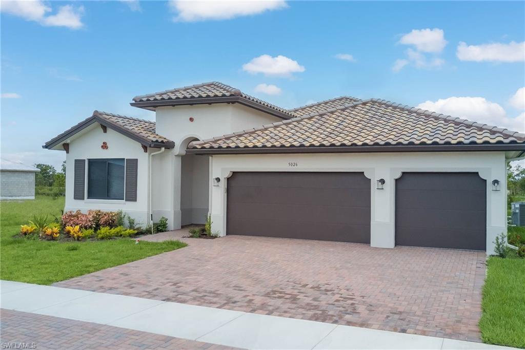 Mediterranean / spanish house with an attached garage, decorative driveway, a front yard, and stucco siding