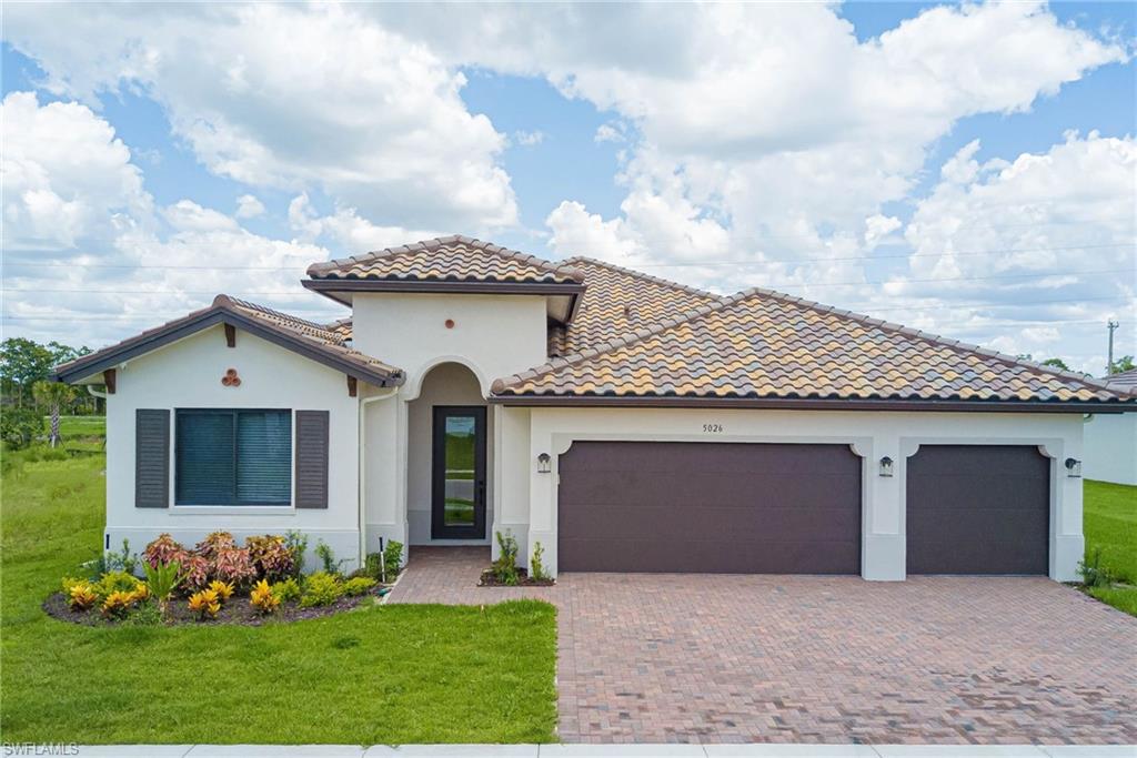 Mediterranean / spanish house featuring an attached garage, decorative driveway, a front yard, and stucco siding