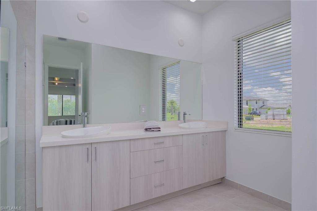 Full bath featuring double vanity and tile patterned flooring