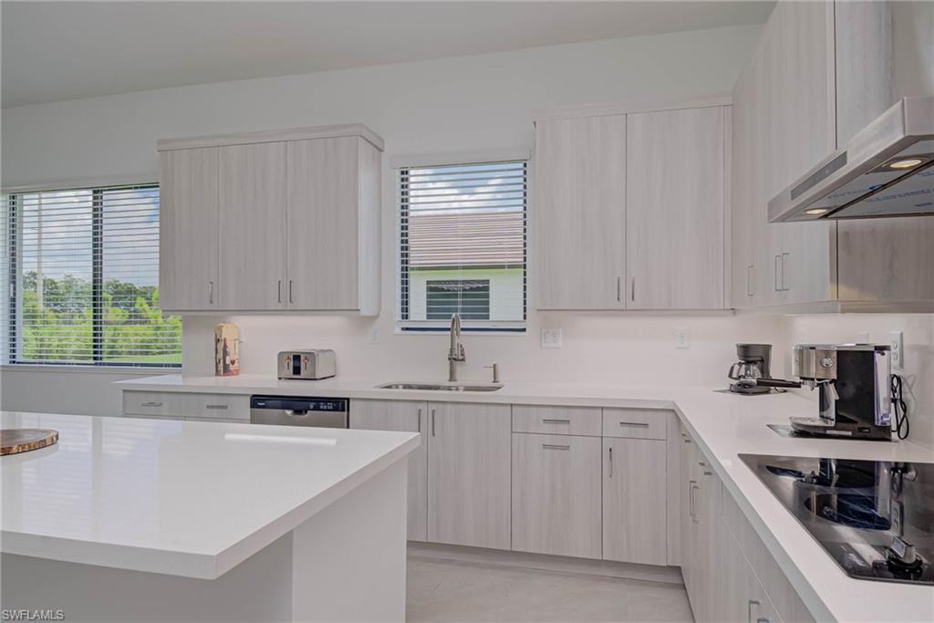 Kitchen with ventilation hood, black electric cooktop, and light countertops
