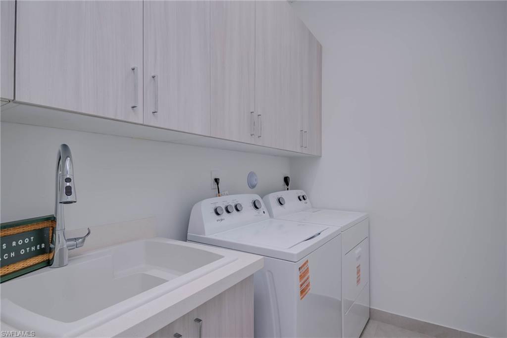 Washroom with cabinet space, washer and dryer, and light tile patterned floors