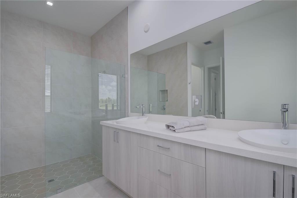 Full bath featuring double vanity, walk in shower, and tile patterned floors
