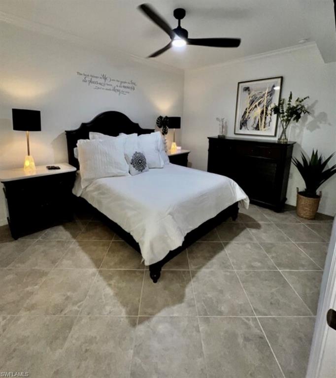 Bedroom featuring light tile patterned floors, crown molding, and a ceiling fan