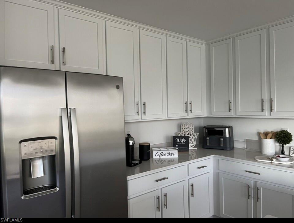 Kitchen featuring stainless steel fridge and white cabinetry