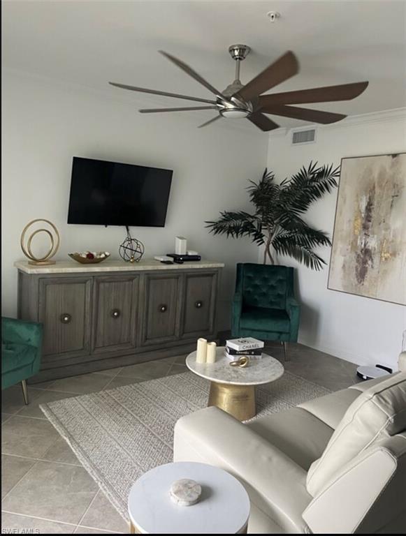 Living area with crown molding, ceiling fan, and light tile patterned flooring