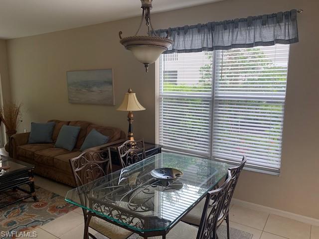 Living area with a ceiling fan, light tile patterned floors, and a sunroom
