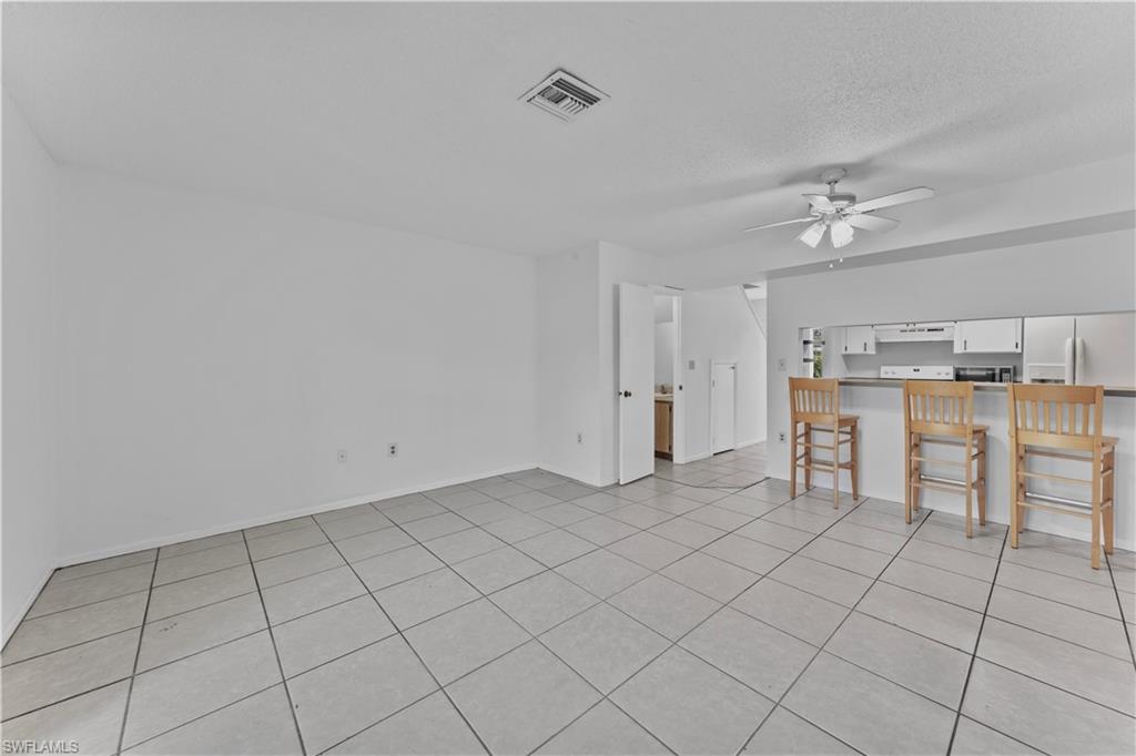 Unfurnished living room featuring a textured ceiling, light tile patterned floors, and ceiling fan