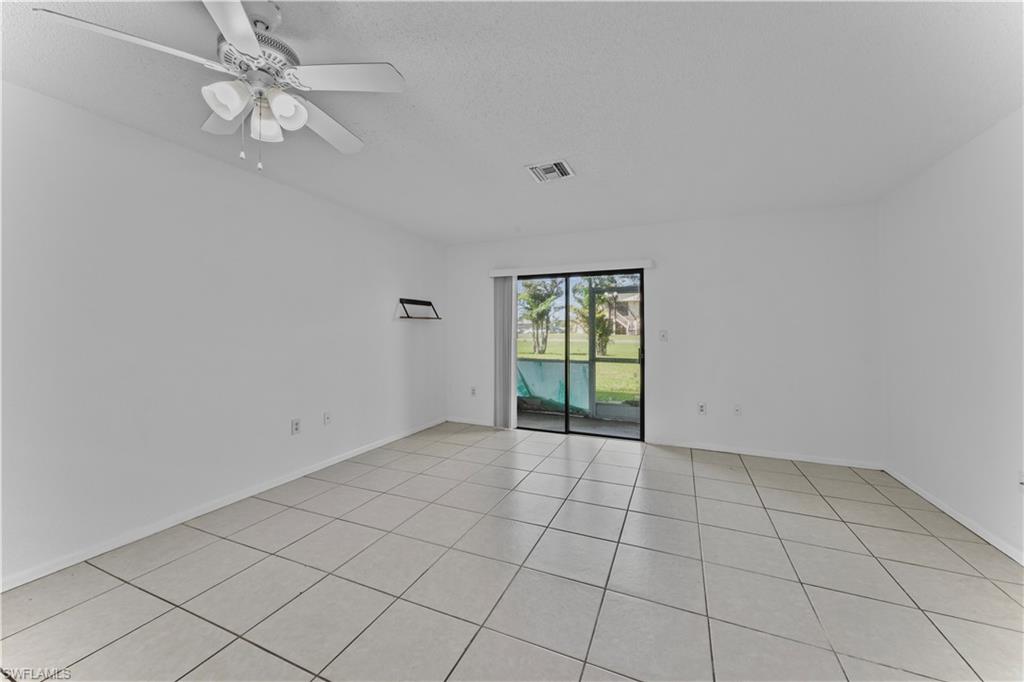 Unfurnished room with light tile patterned flooring, ceiling fan, and a textured ceiling