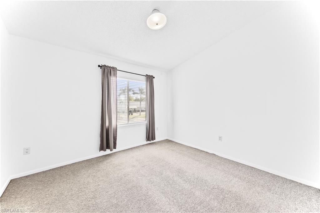 Carpeted empty room with lofted ceiling