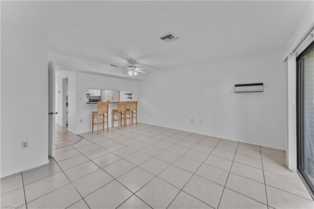 Unfurnished living room featuring a textured ceiling, ceiling fan, and light tile patterned floors