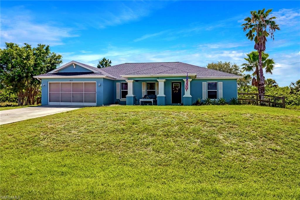 Ranch-style house featuring an attached garage, driveway, stucco siding, and a front yard