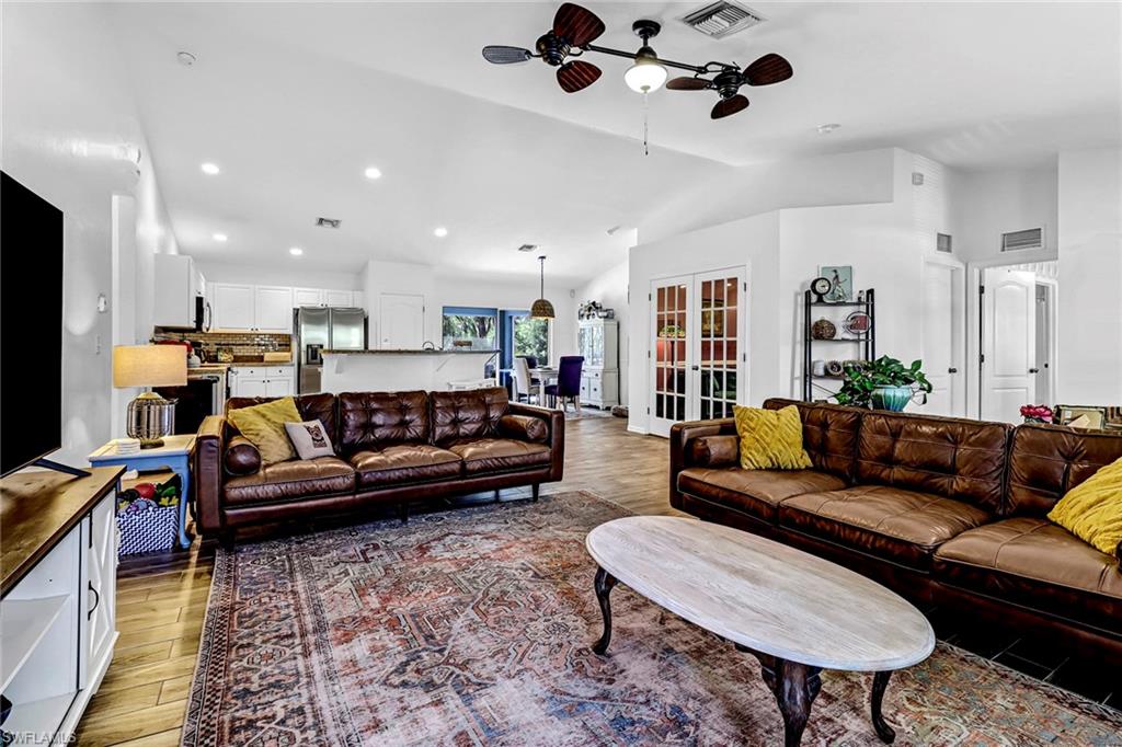 Living area with light wood-style flooring, ceiling fan, vaulted ceiling, and recessed lighting
