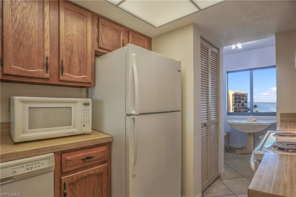 Kitchen featuring brown cabinets, white appliances, and light tile patterned floors