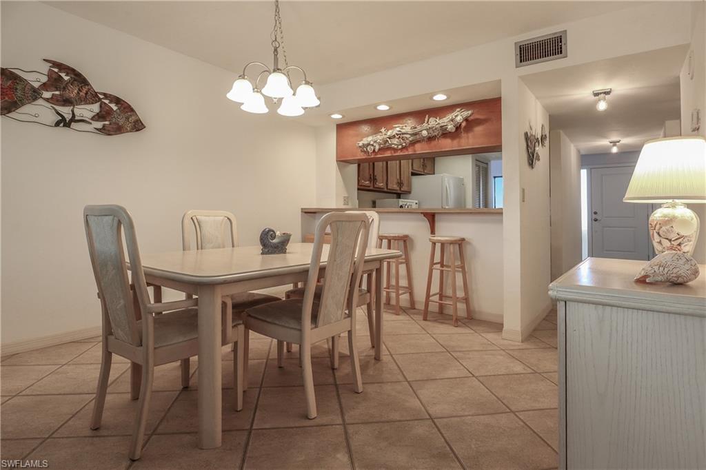 Dining area featuring light tile patterned flooring, recessed lighting, and a chandelier