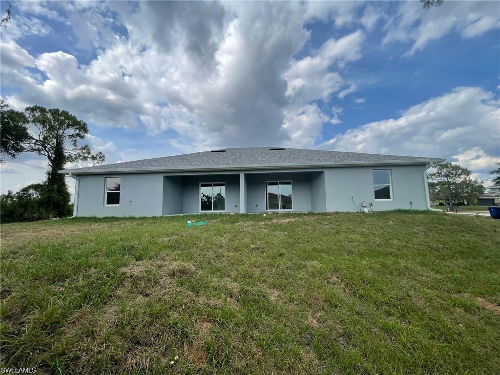 Back of property with stucco siding and a lawn