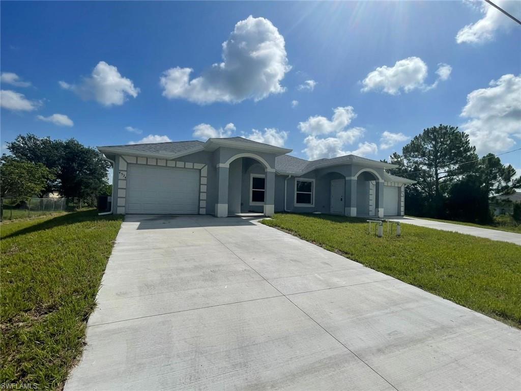 Ranch-style house with an attached garage, driveway, a front lawn, and stucco siding