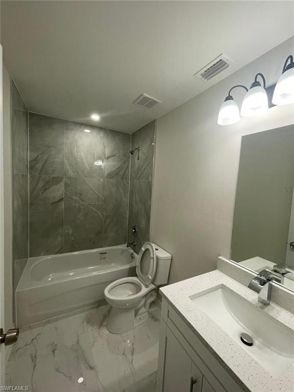 Bathroom with vanity, bathing tub / shower combination, and marble look tiles