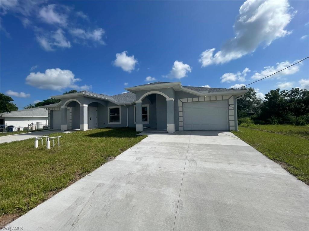 Single story home with a garage, driveway, a front yard, and stucco siding