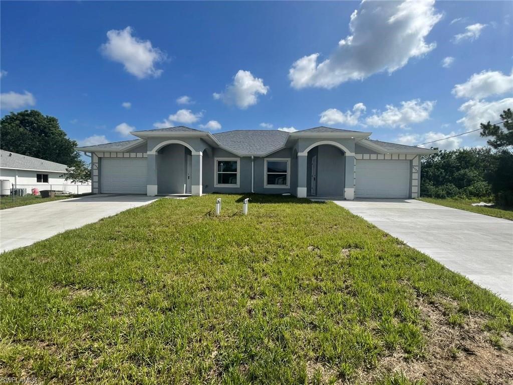 Single story home featuring driveway, a front lawn, a garage, and stucco siding