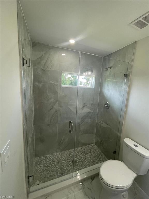 Bathroom with marble finish floors, a stall shower, and recessed lighting