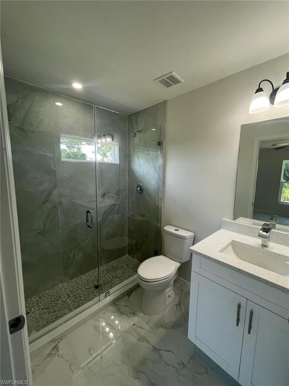 Bathroom featuring vanity, a stall shower, marble finish flooring, healthy amount of natural light, and recessed lighting