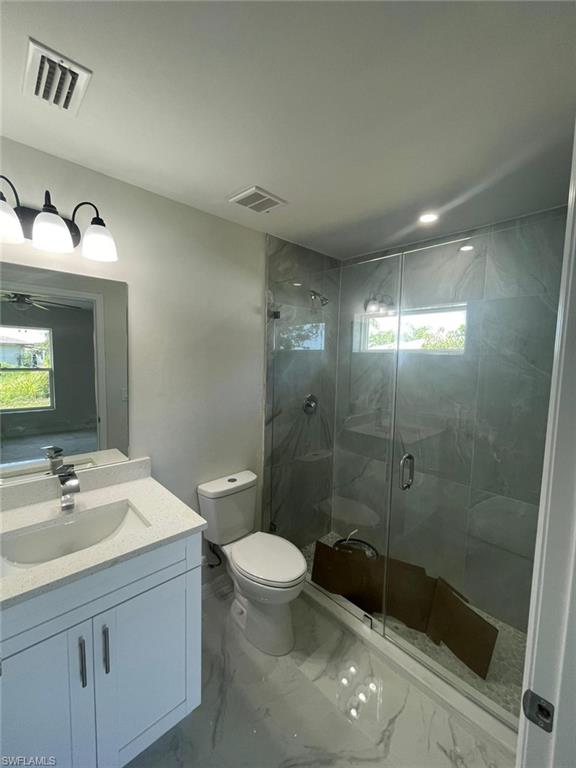Full bathroom featuring vanity, a shower stall, and marble finish flooring