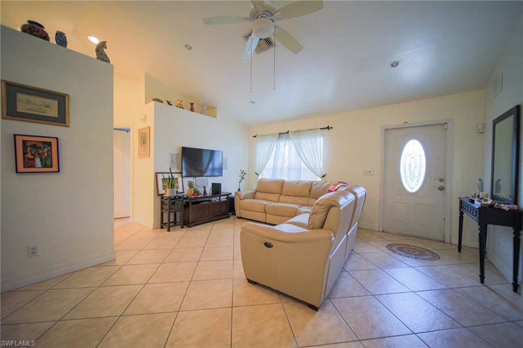 Living area featuring vaulted ceiling, a ceiling fan, and light tile patterned flooring