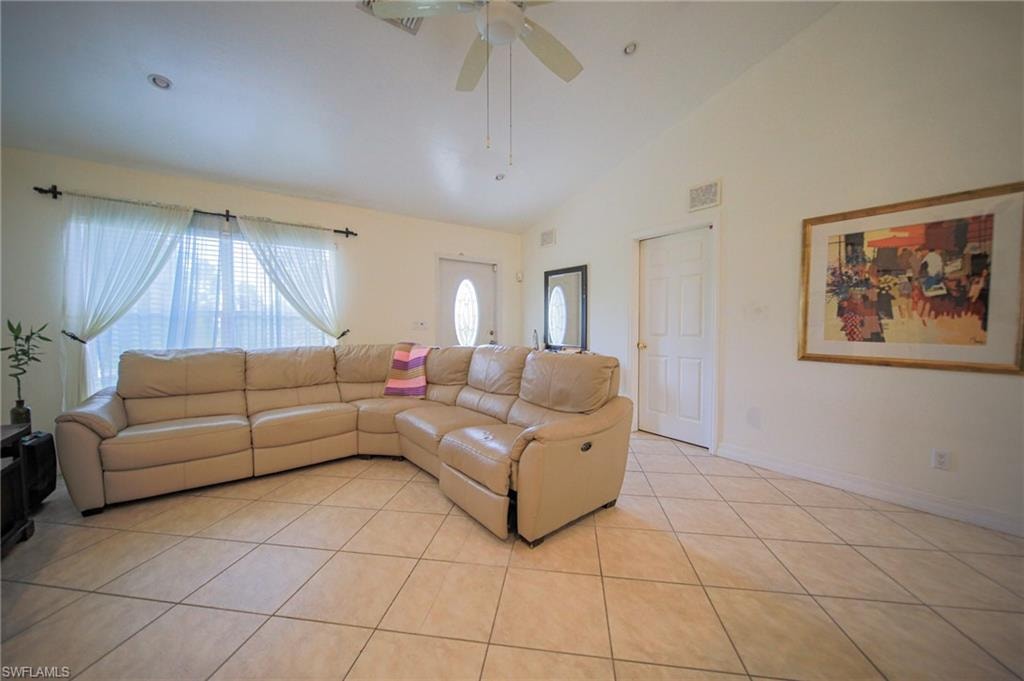 Living area with light tile patterned floors, ceiling fan, and high vaulted ceiling