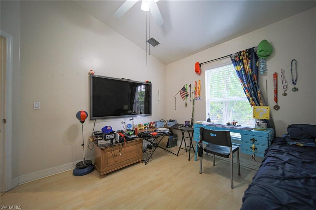 Bedroom with lofted ceiling, wood finished floors, and ceiling fan