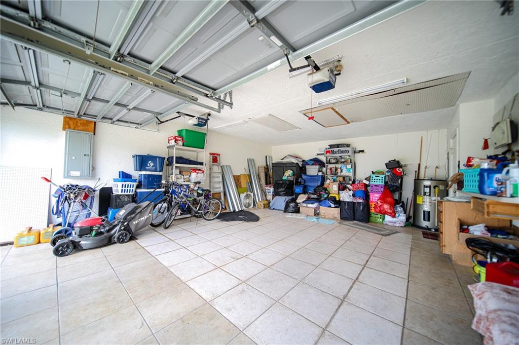 Garage featuring electric water heater, a garage door opener, and electric panel