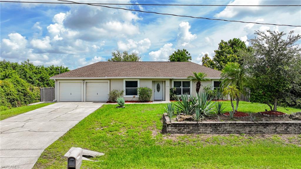 Ranch-style house with a garage, a front lawn, concrete driveway, and stucco siding