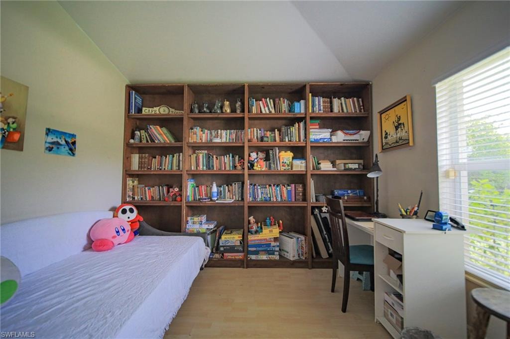 Bedroom featuring multiple windows, lofted ceiling, and light wood finished floors