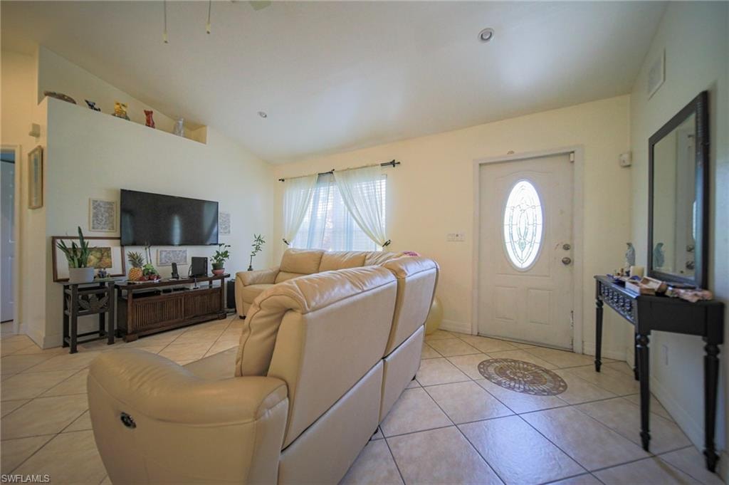 Living area featuring light tile patterned flooring and vaulted ceiling