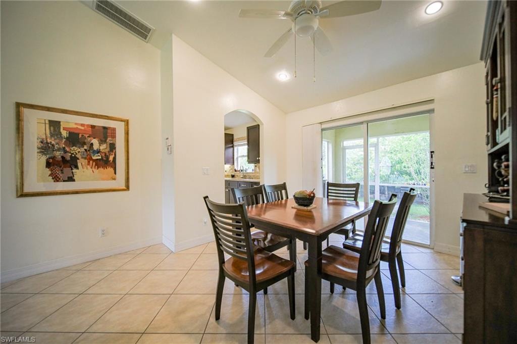 Dining room with vaulted ceiling, ceiling fan, arched walkways, light tile patterned floors, and recessed lighting