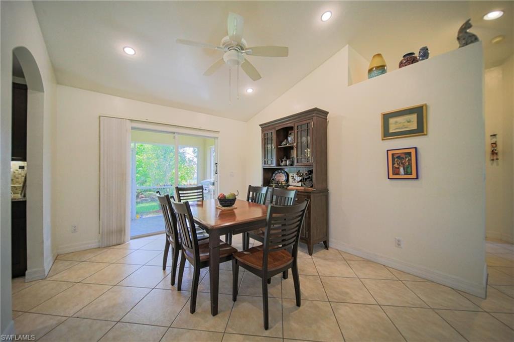 Dining room featuring ceiling fan, arched walkways, lofted ceiling, recessed lighting, and light tile patterned floors