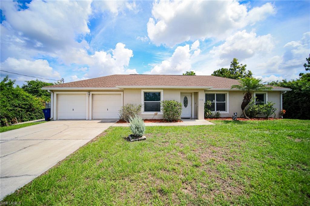 Single story home featuring a garage, stucco siding, concrete driveway, and a front lawn
