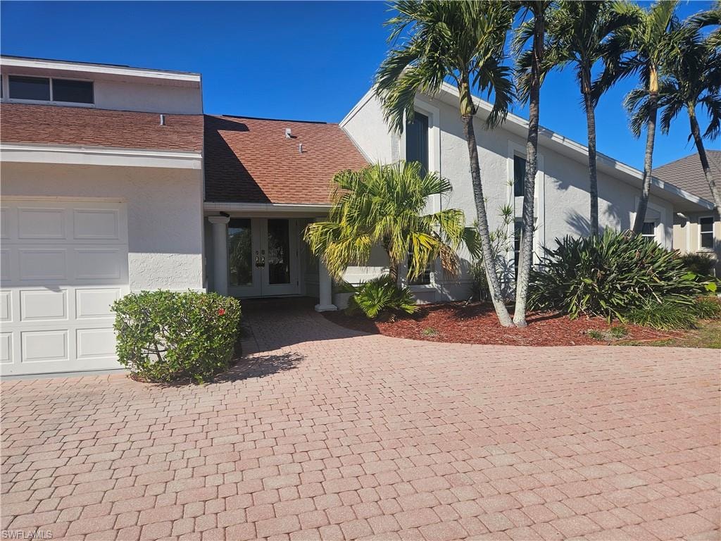 View of front of home featuring french doors, stucco siding, and driveway