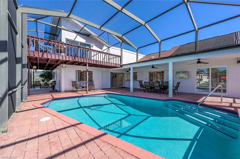 Swimming pool featuring ceiling fan, a patio, outdoor dining area, and glass enclosure