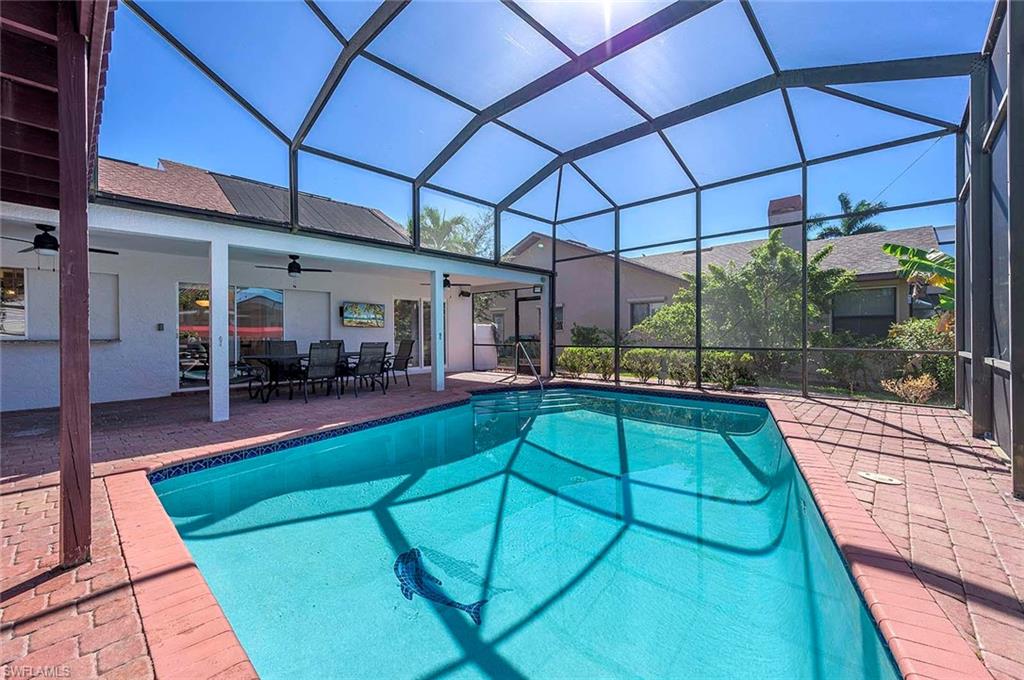 Swimming pool with a ceiling fan, a patio area, outdoor dining space, and glass enclosure