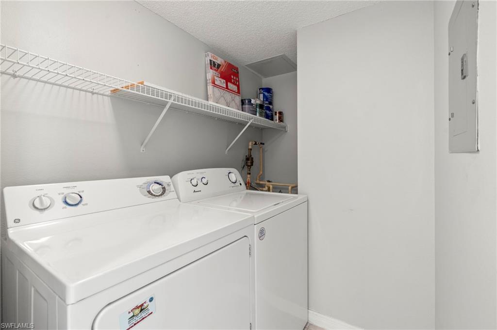 Laundry area featuring washer and clothes dryer, electric panel, and a textured ceiling