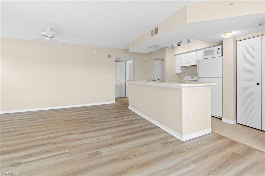Kitchen featuring white appliances, white cabinets, light wood-style floors, ceiling fan, and light countertops