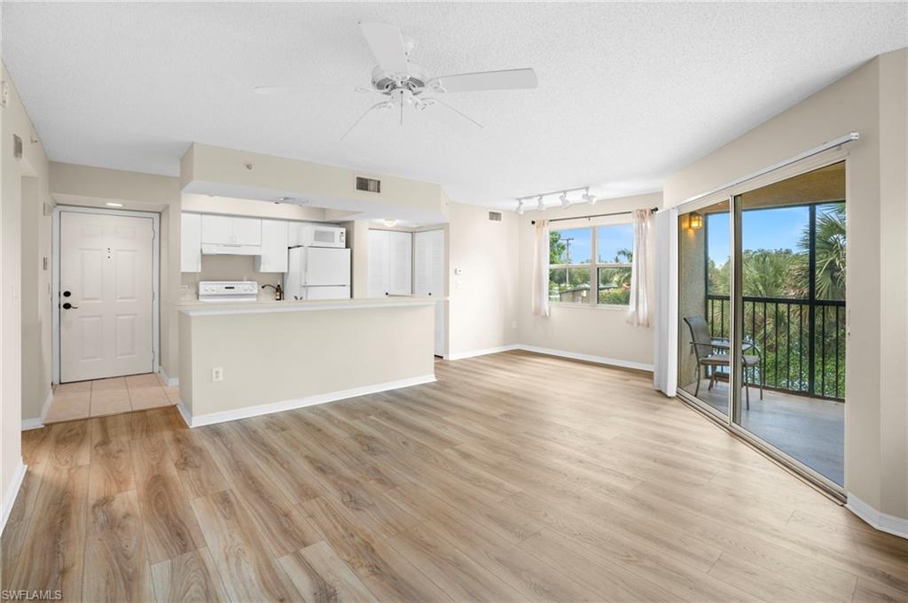 Unfurnished living room with a ceiling fan, light wood-type flooring, rail lighting, and a textured ceiling