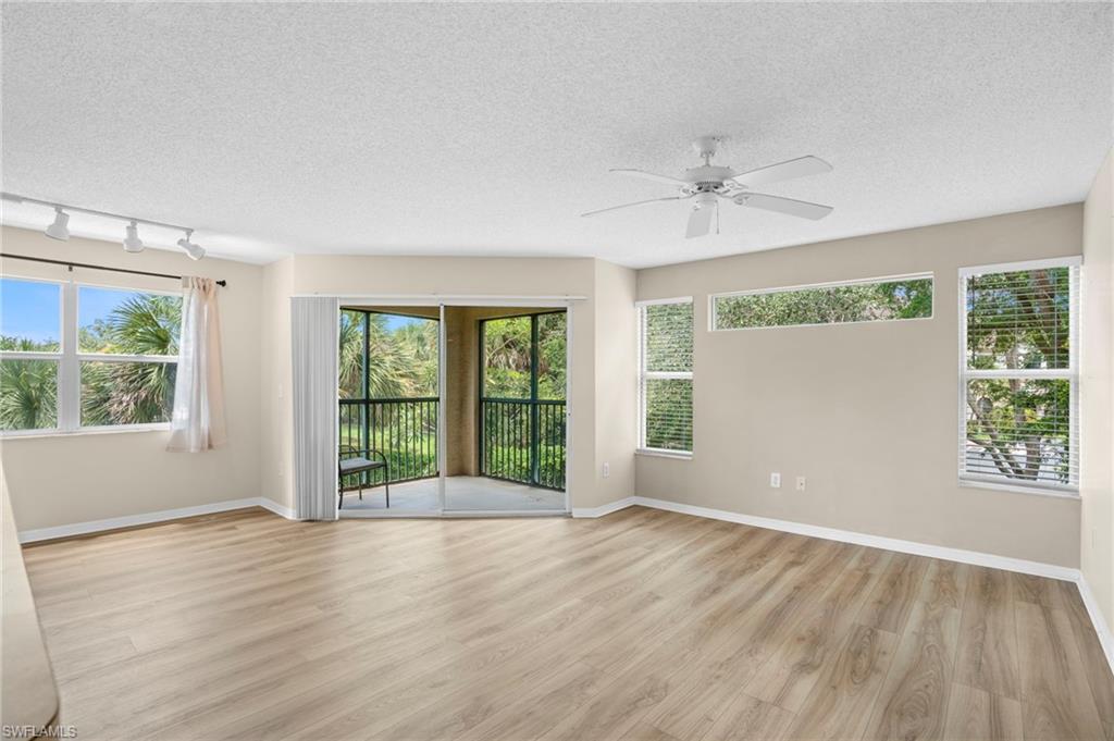 Unfurnished room with a textured ceiling, light wood finished floors, ceiling fan, healthy amount of natural light, and rail lighting
