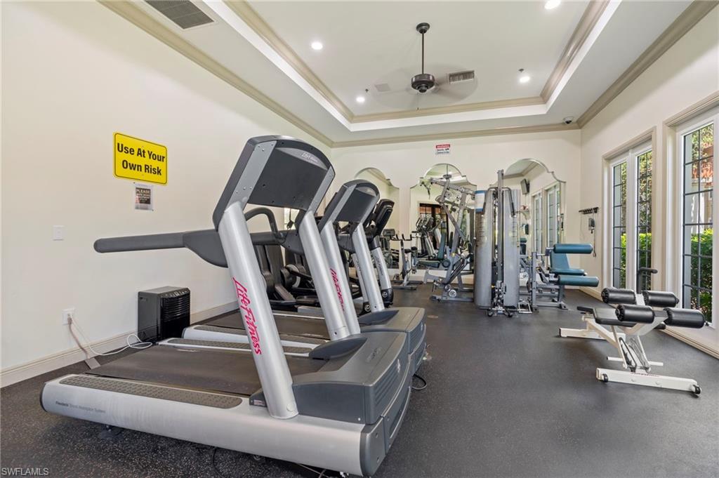 Gym with ceiling fan, crown molding, a tray ceiling, and recessed lighting