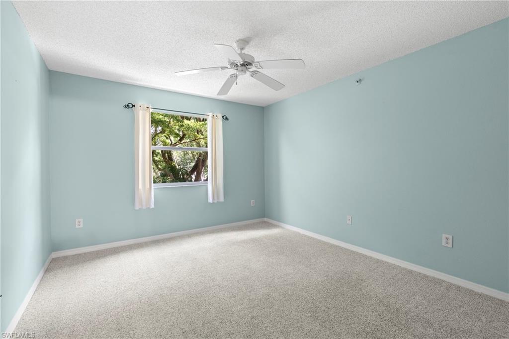 Carpeted empty room featuring a textured ceiling and ceiling fan