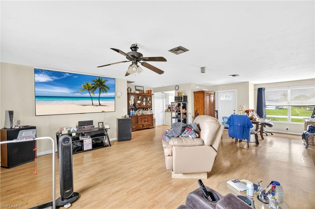 Living area with ceiling fan and light wood finished floors
