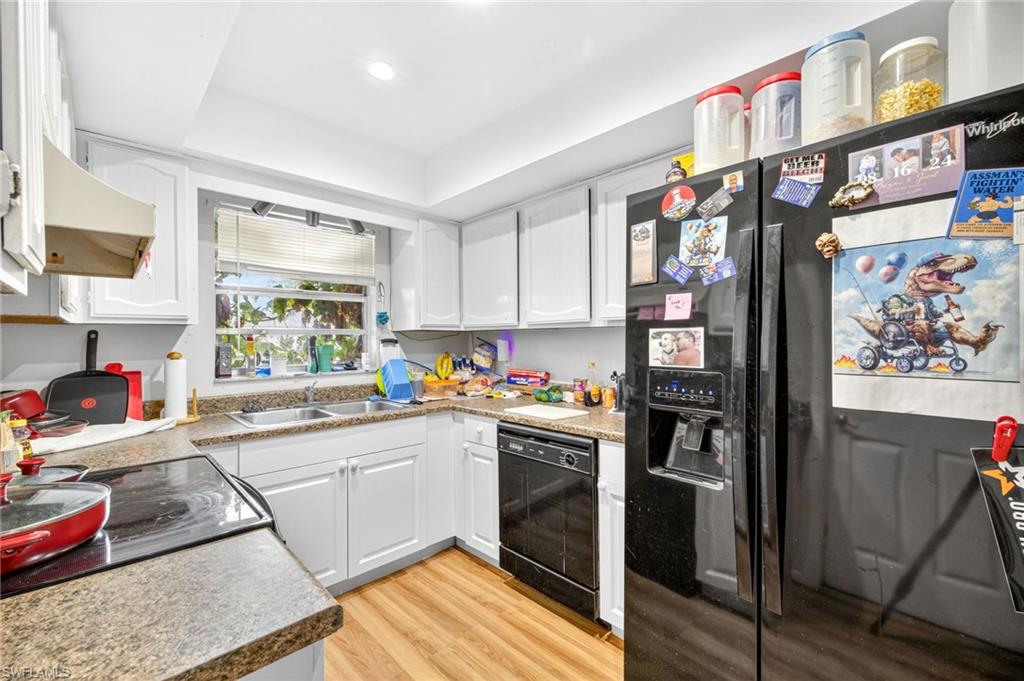 Kitchen featuring black appliances, white cabinets, light wood-style flooring, and recessed lighting