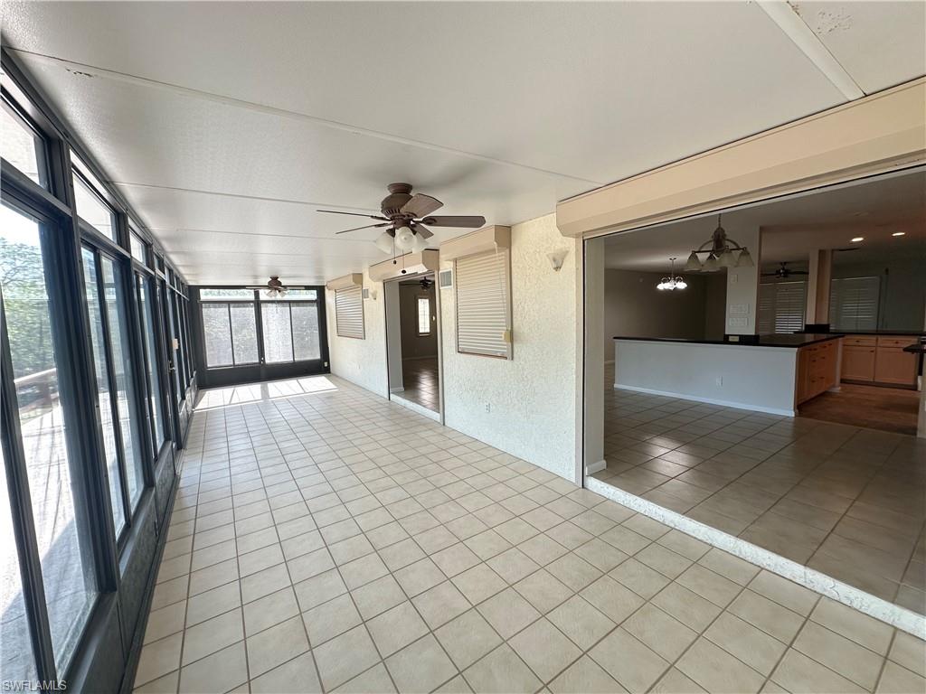 Unfurnished living room with a chandelier, a ceiling fan, and light tile patterned floors