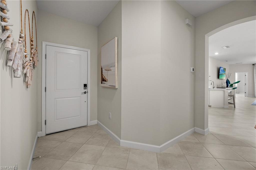 Hallway featuring arched walkways, light tile patterned floors, and recessed lighting
